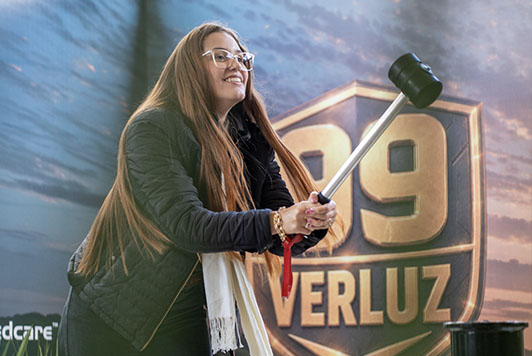 Visitantes participam do desafio Martelo da Força no estande da Verluz durante a Showtec 2026 tentando alcançar o Vigor 99.